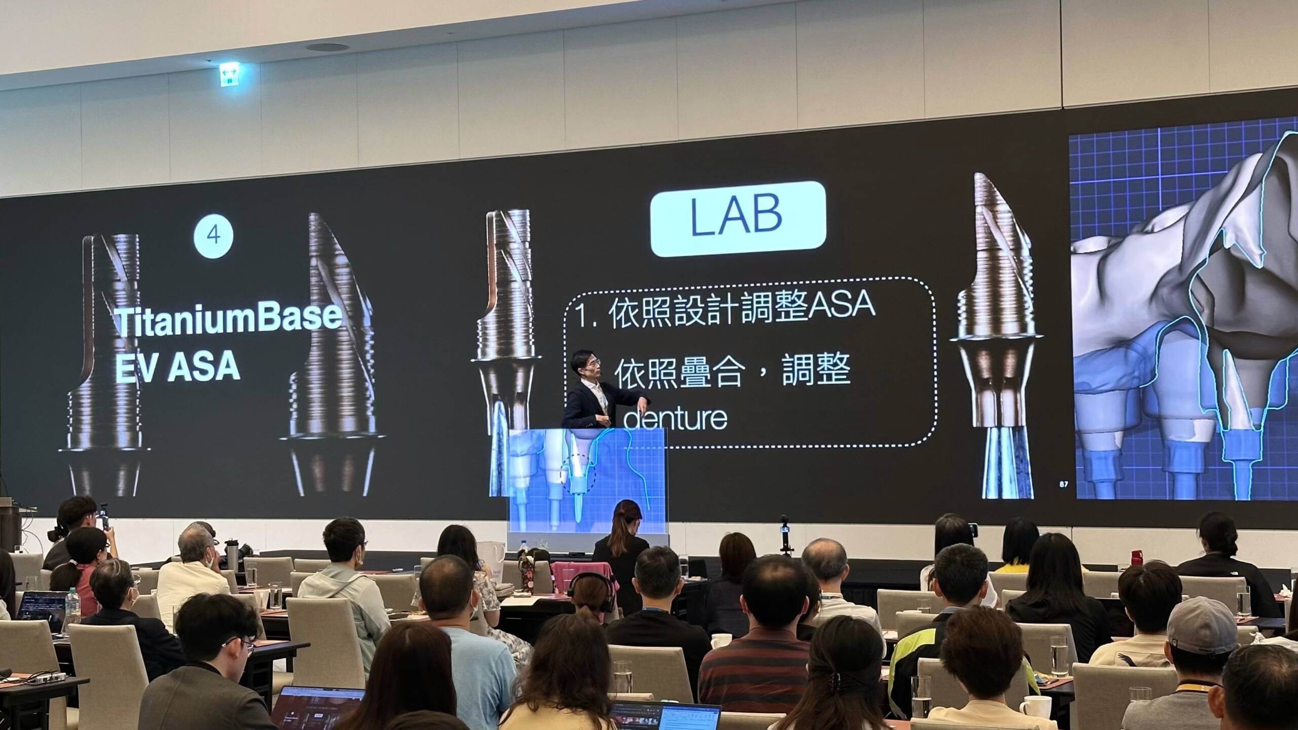 從觀眾席視角拍攝曹皓崴醫師演講,舞台大螢幕正展示植牙數位工作流程與 TitaniumBase 零件設計。 從觀眾席視角拍攝曹皓崴醫師演講,舞台大螢幕正展示植牙數位工作流程與 TitaniumBase 零件設計。
